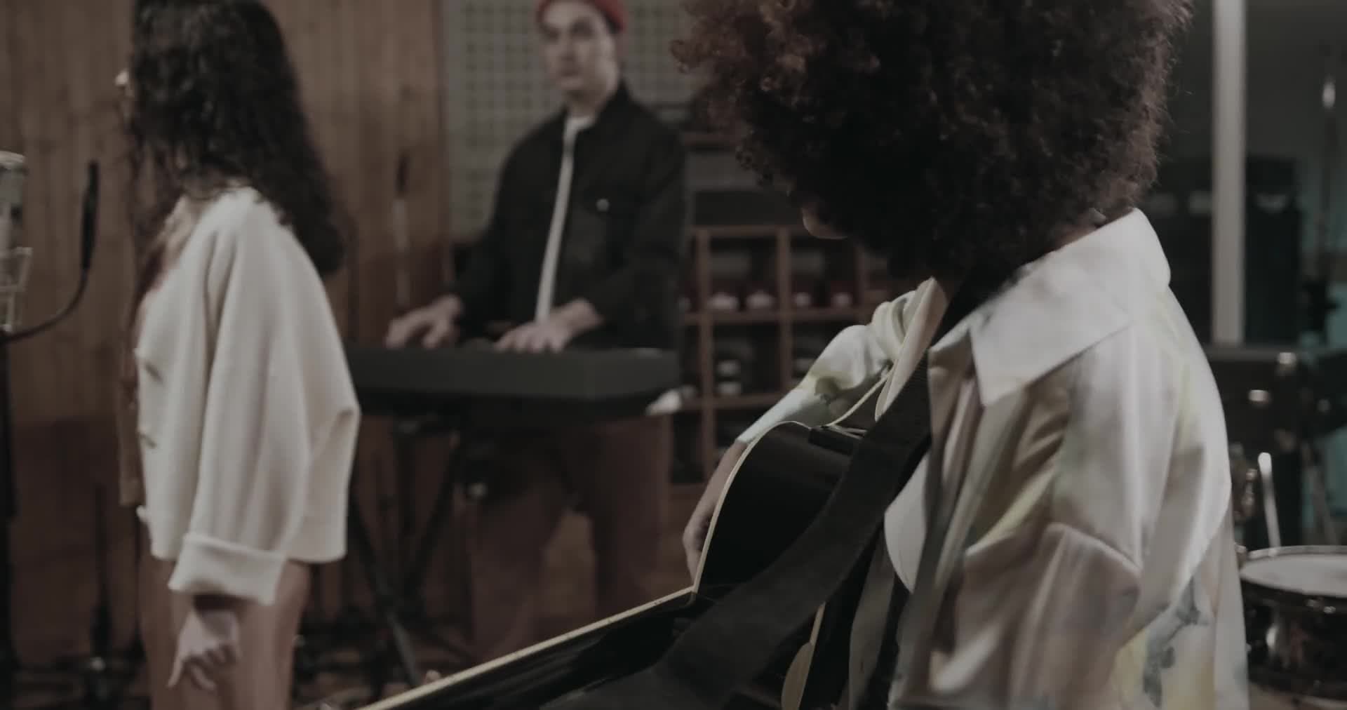 Musicians recording together in a wood-panelled studio